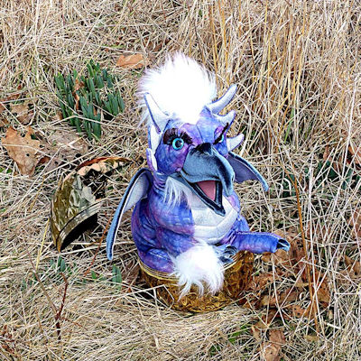 image of what appears to be a small stuffed dragon hatching from a gold shell at Robinhood Farm, slightley edited by Charlie Ipcar, Graphic &copy; 2026, Ipbar Productions, all rights reserved.